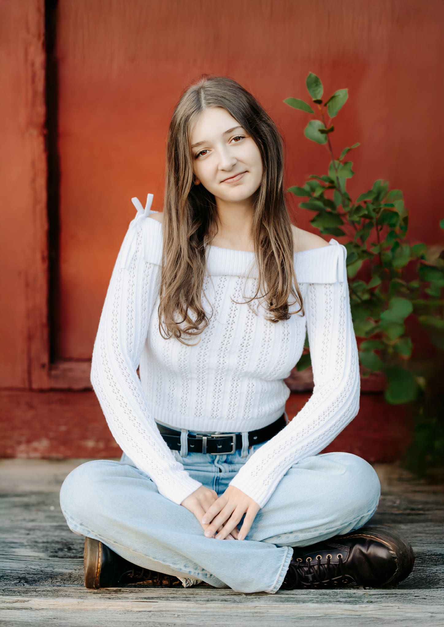 High school senior girl sitting for her senior photos wearing her favorite jeans and sweater combo.