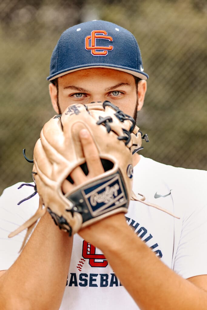 High school senior showing off his baseball glove and his extreme focus during his senior photos.
