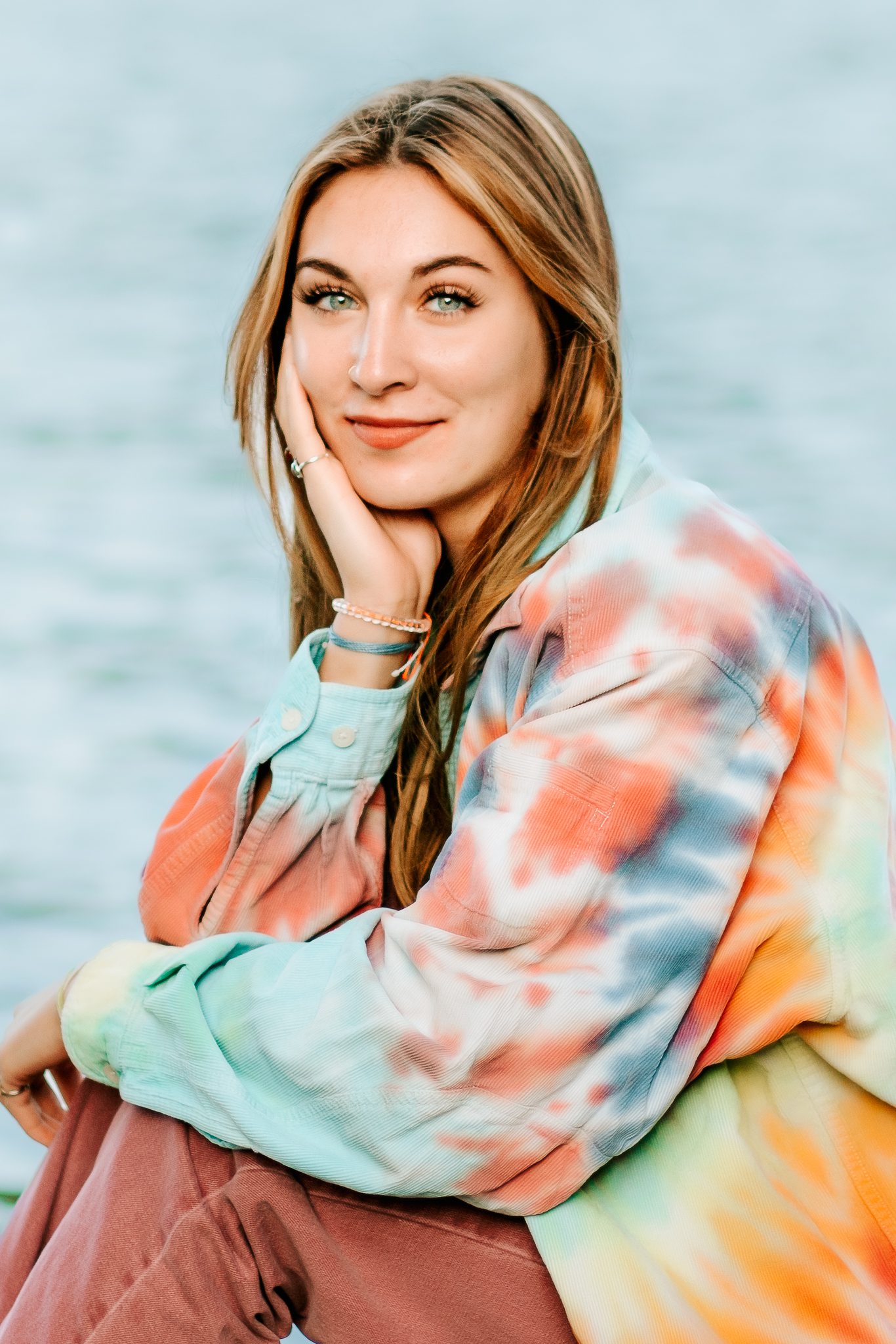 High school sitting for her senior photos with a bright jacket along a river in New Hampshire.