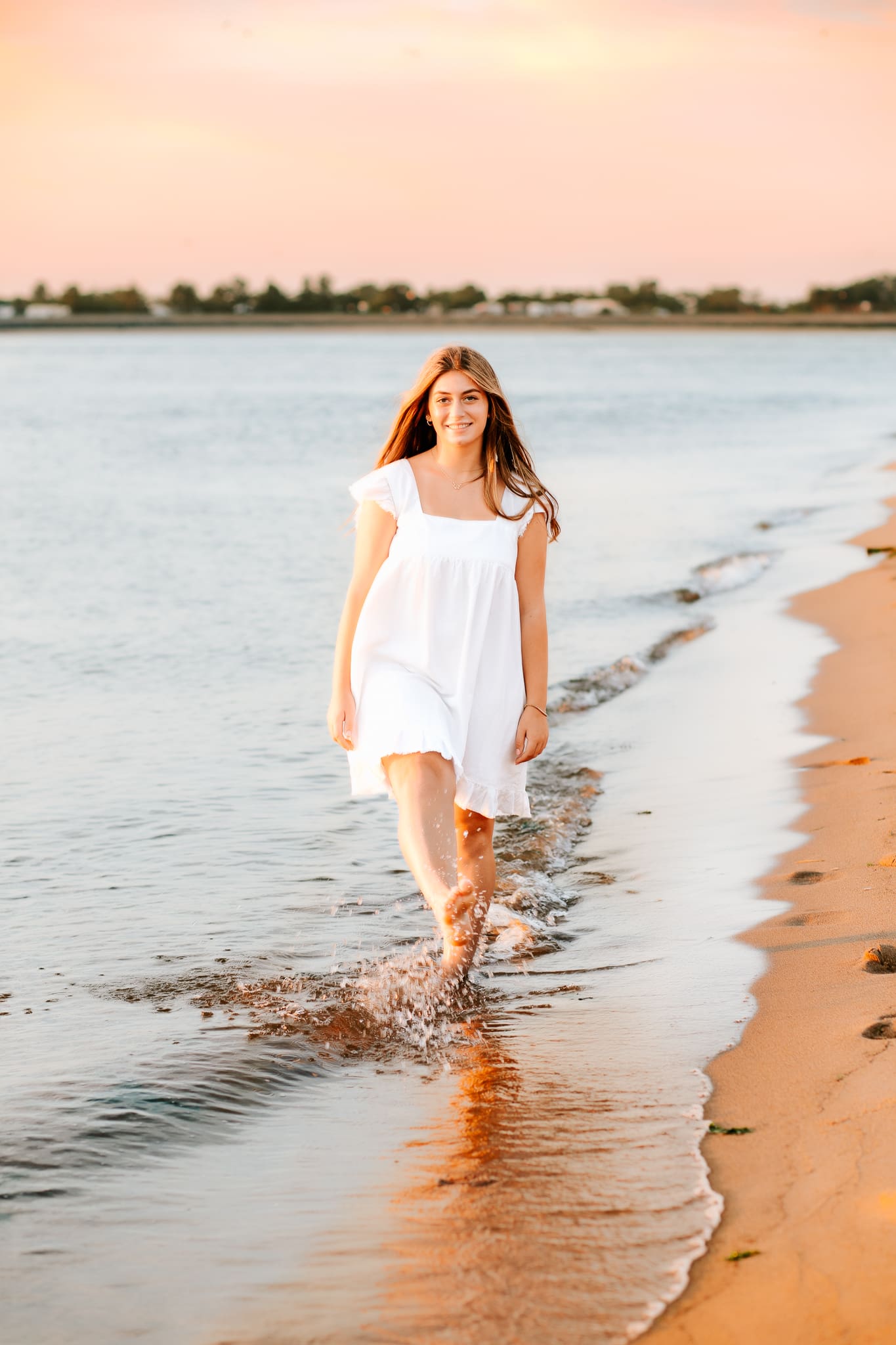 Summer season photo of a high school senior splashing in the ocean  for her senior photos.