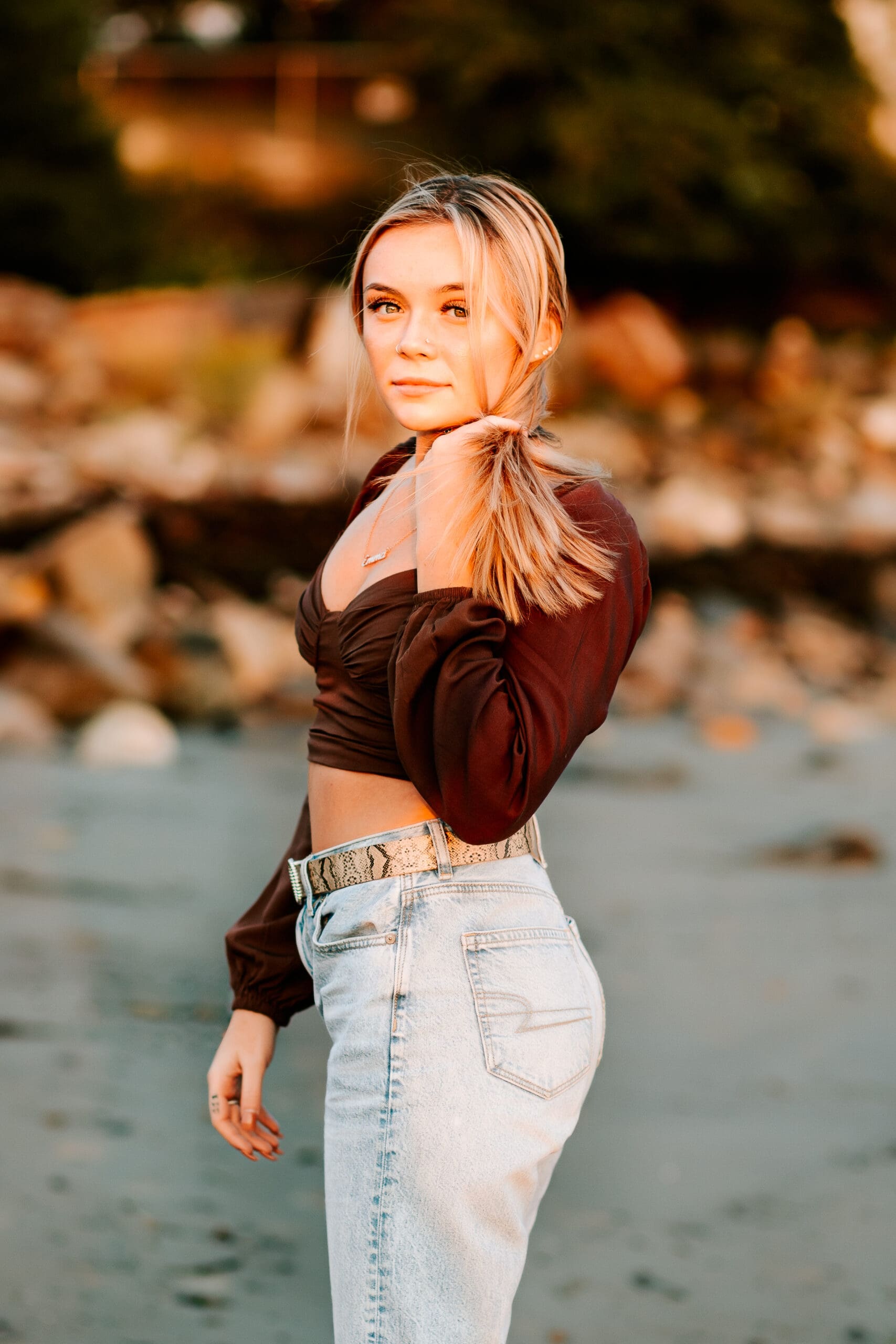 High school senior dressed perfectly for her beachfront senior photos with her light wash jeans and dark brown top.