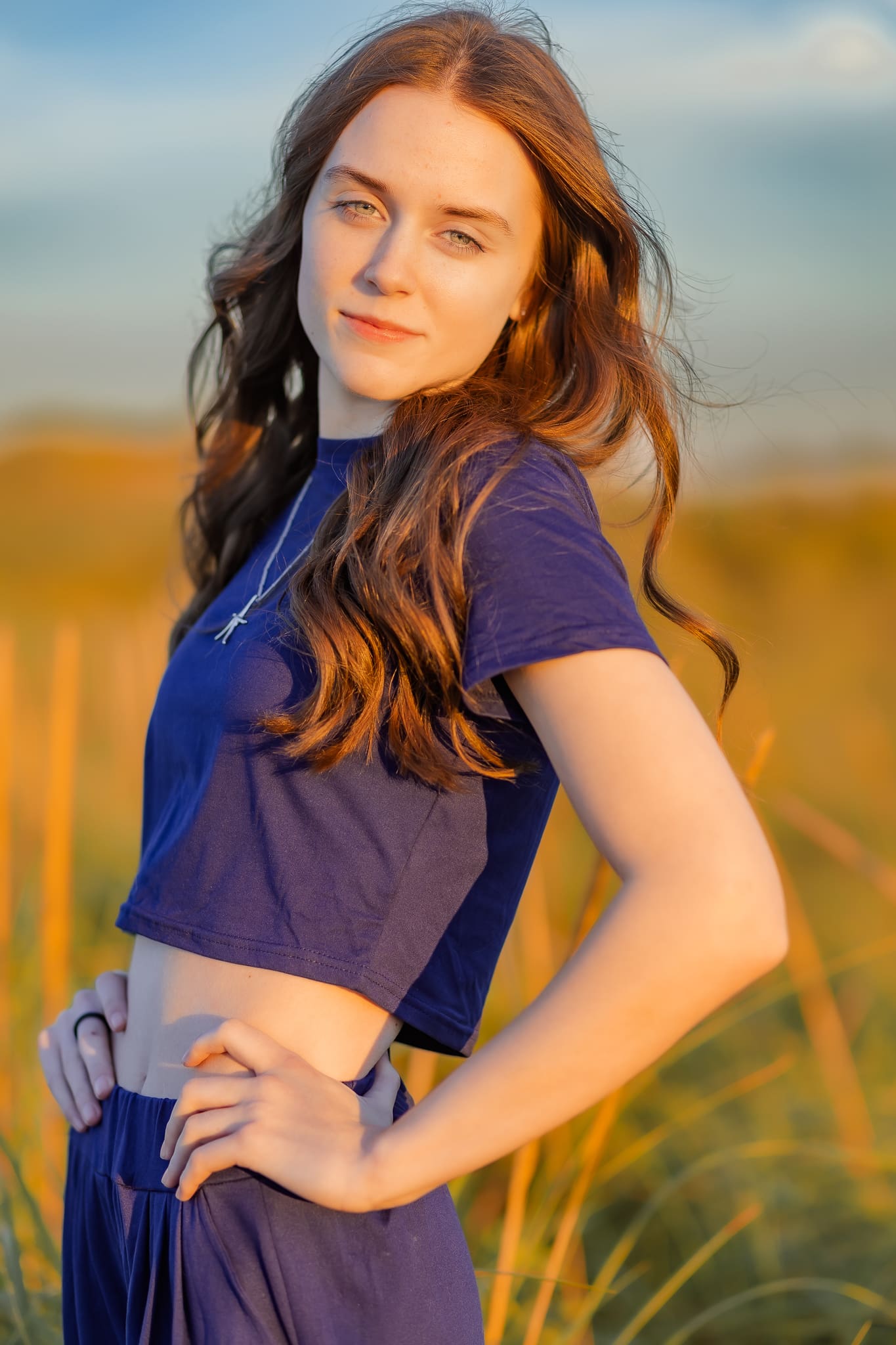 Glowing sunset brightens this senior girl's face during her summer senior photo session.