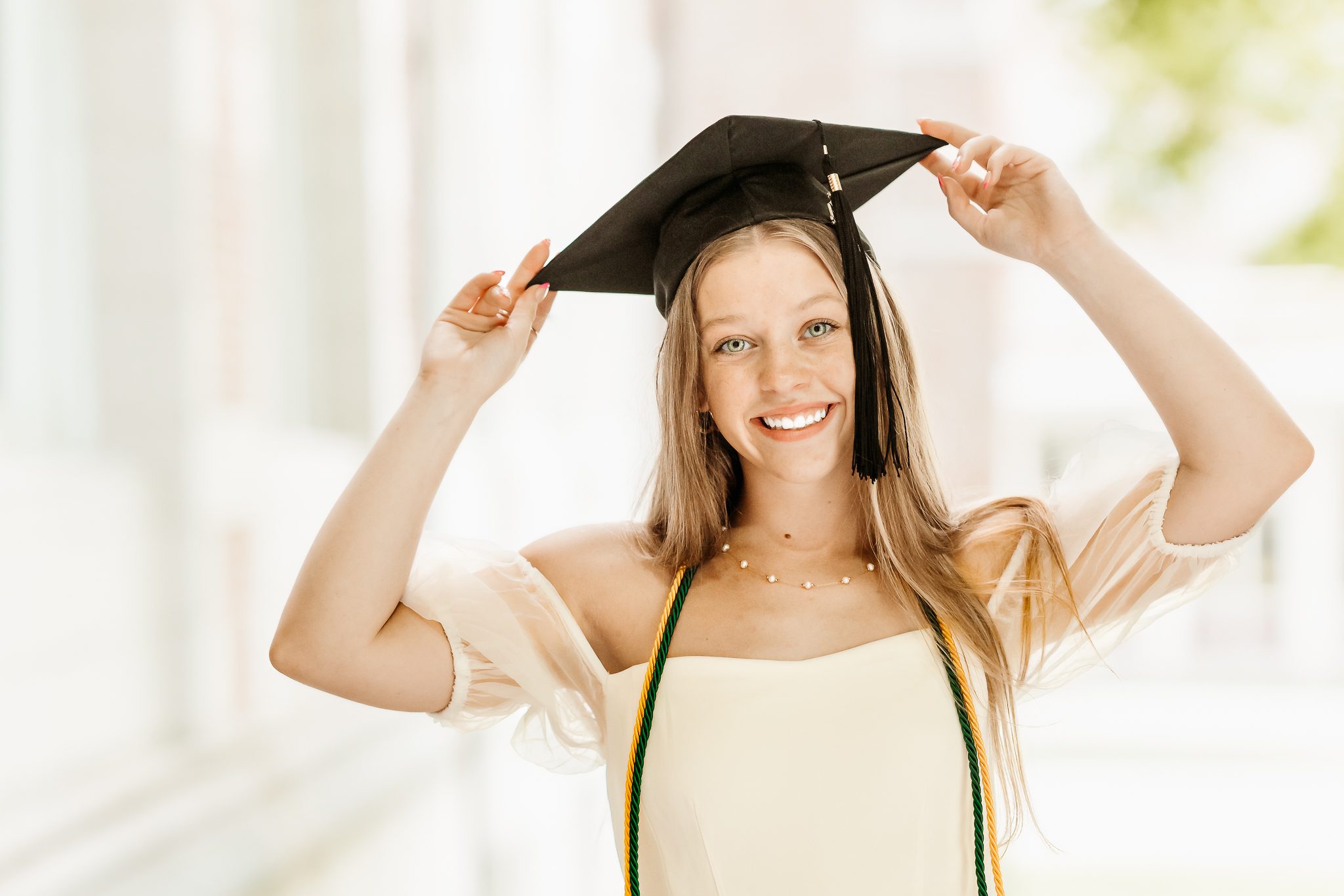 Senior graduate posing with her cap and regalia cords in Boston, Massachusetts.