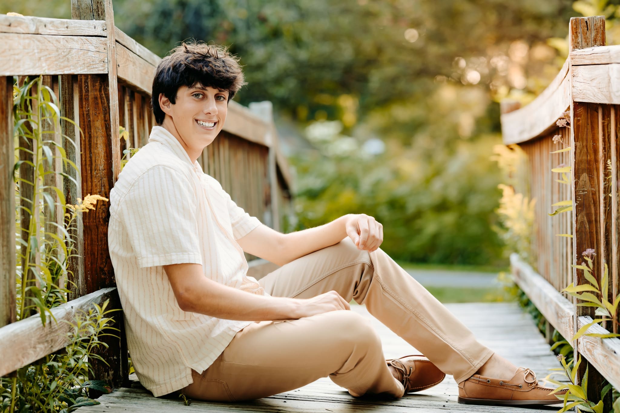 Boston Senior seated on a walking bridge at the Acton Arboretum for his senior photos. Senior Session Prep