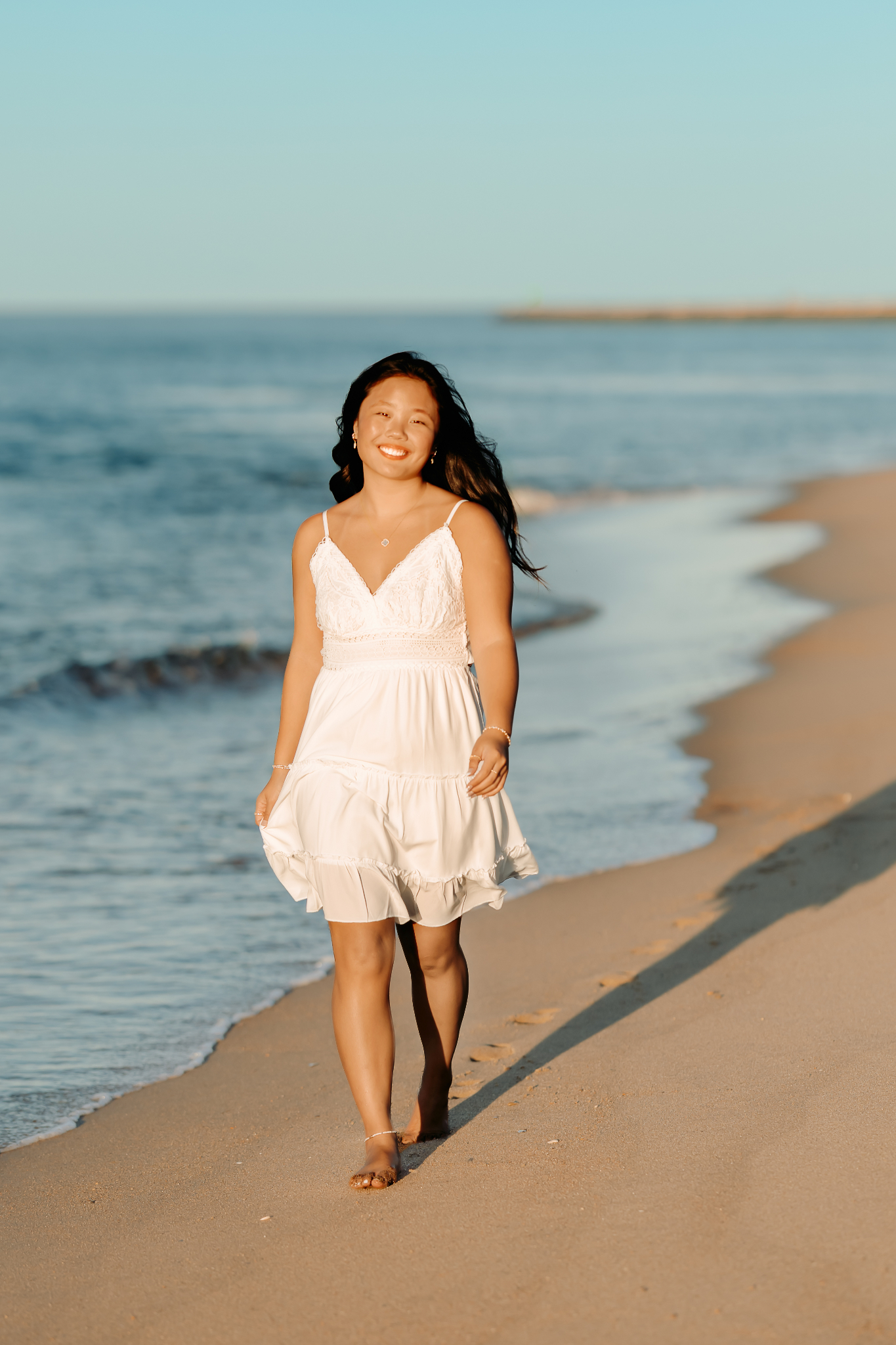 High School senior girl walking along the coastline in Newburyport, MA