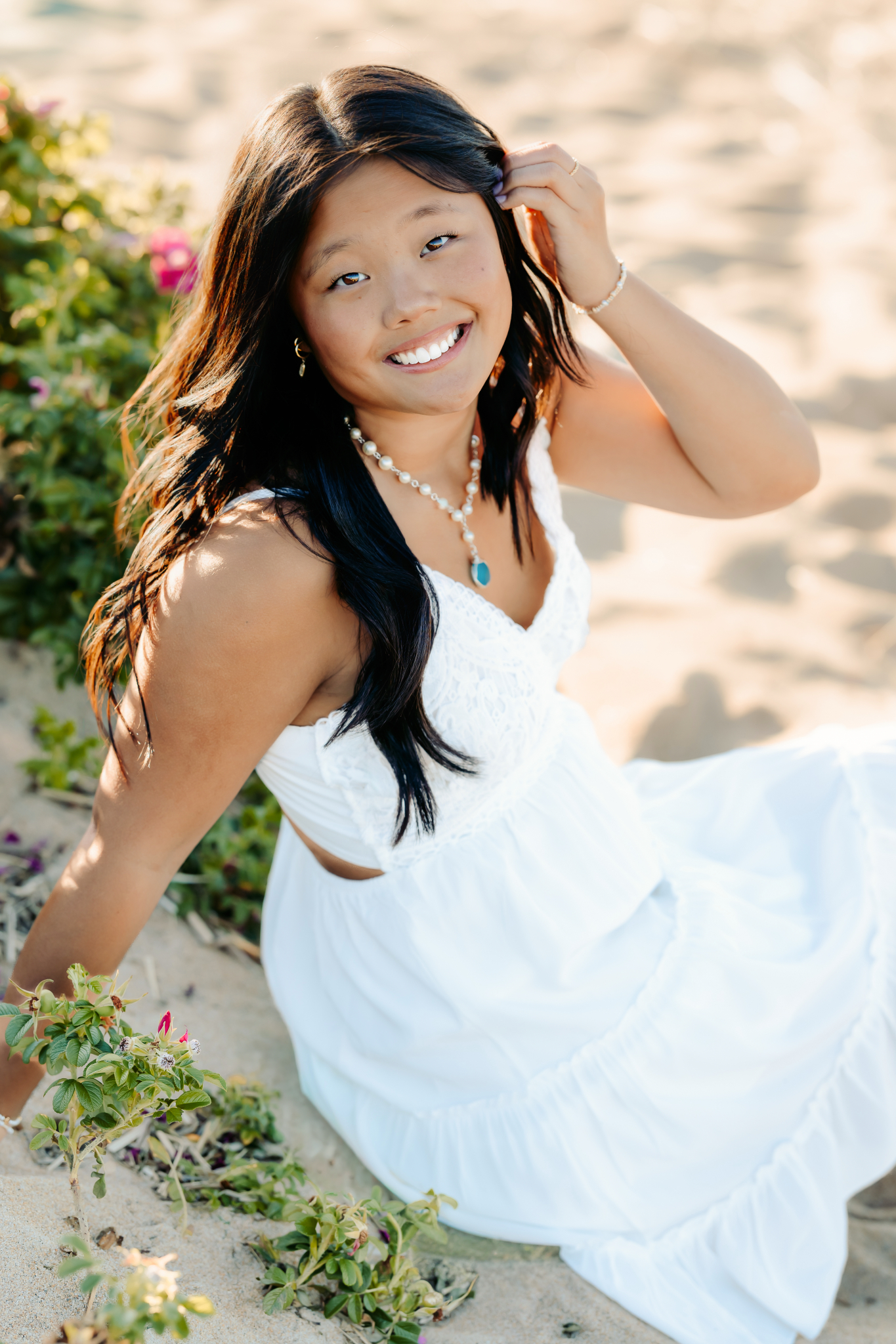 Senior girl sitting among the beach flowers for her senior photos at Plum Island, Newburyport, MA
