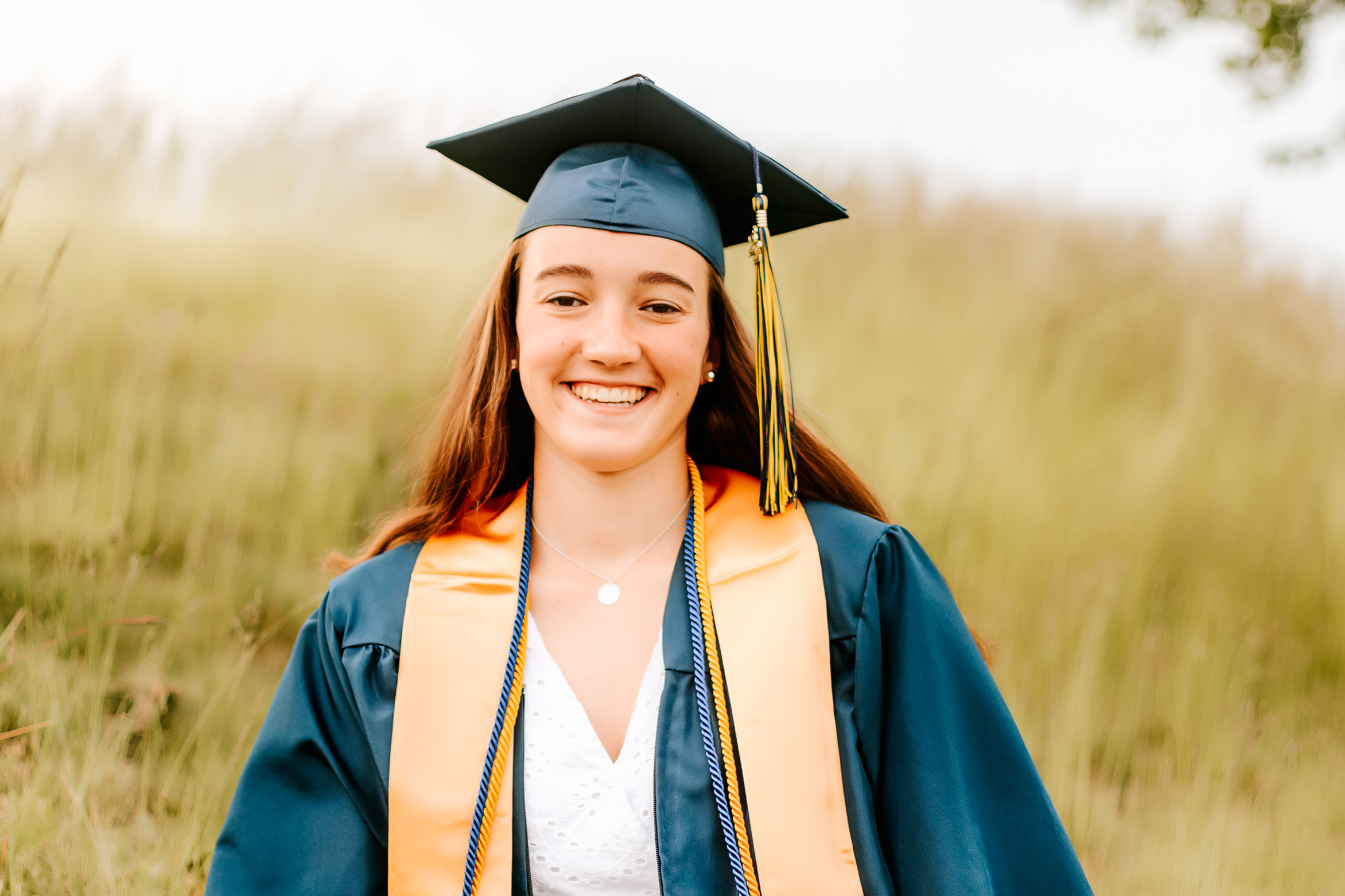 High school graduate smiling in her cap and gown during graduation photos, Andover High School, Andover, MA
