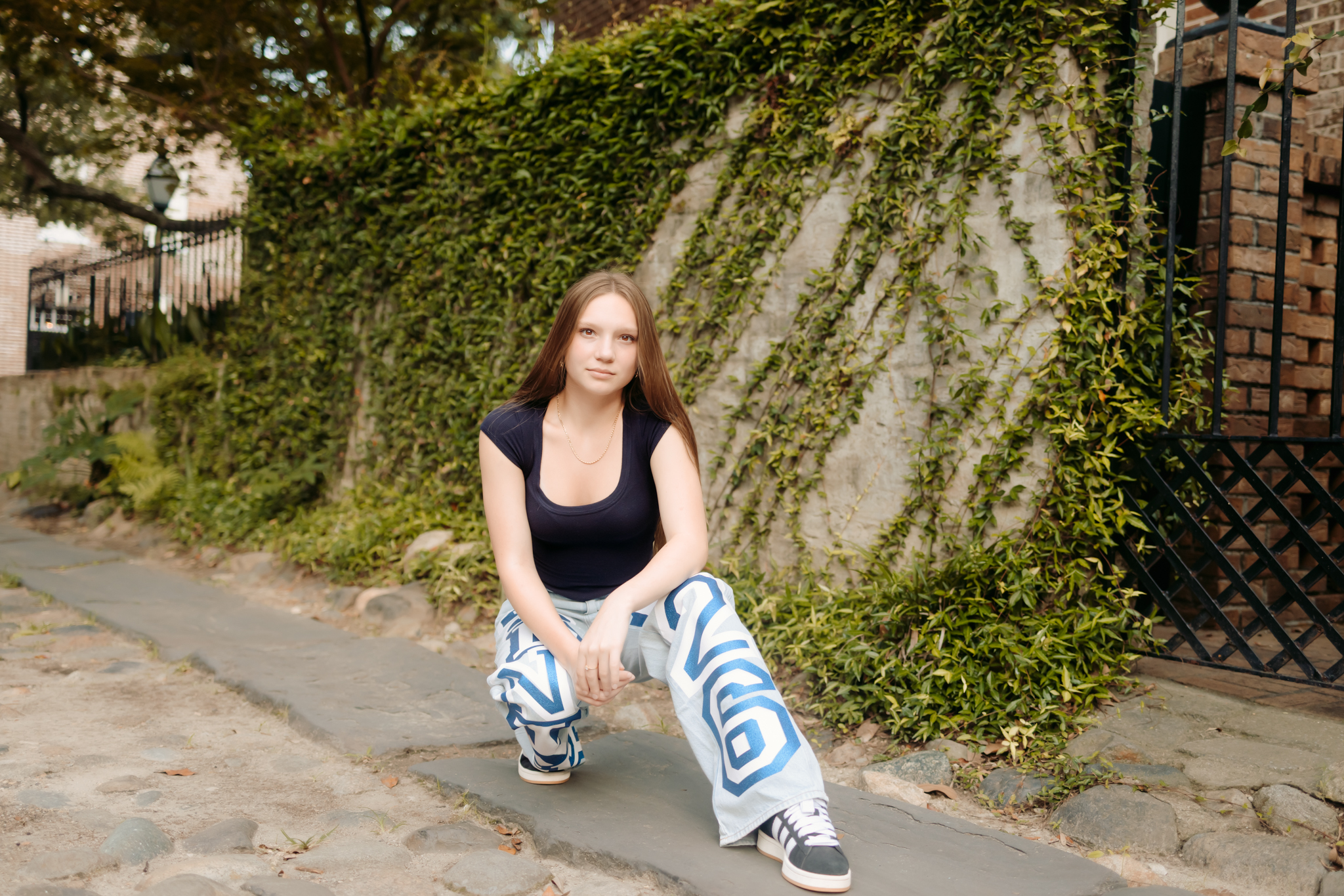 Senior girl posing against an ivy wall in her Senior Year denim