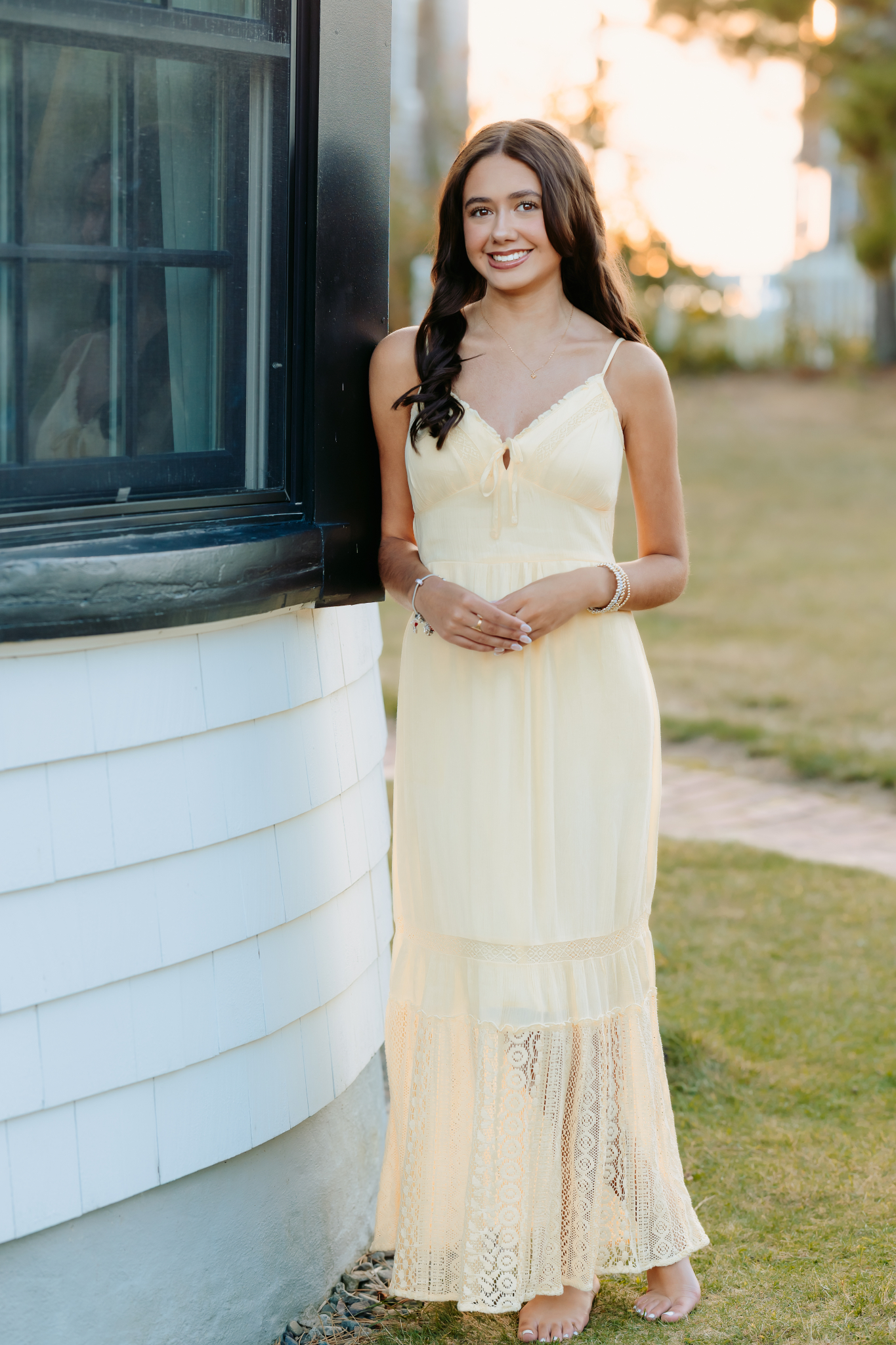 Class of 2027 senior in yellow maxi dress at Plum Island Lighthouse during sunset.